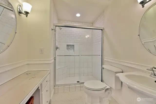 3/4 bathroom with tile surround and tile flooring.