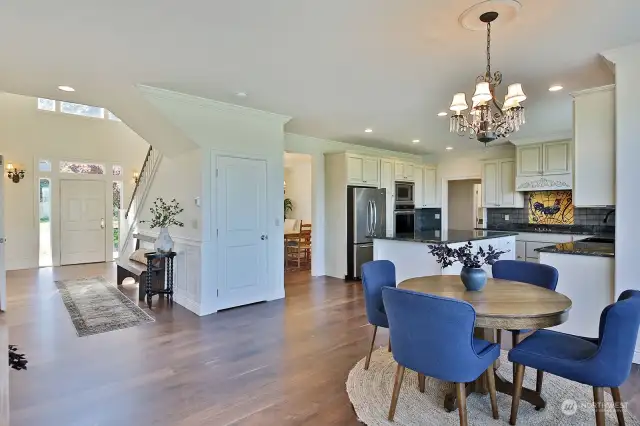 View from the edge of the living room, looking back at the foyer and an expansive view of the kitchen. Doors to the expansive deck is to your back. Door under the stairs is a closet space.