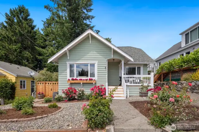 This home has a low-maintenance front yard with roses that are in full bloom and a window box with more flowers.