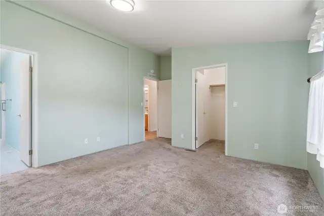 Primary bedroom showing access to bathroom, large closet, and hallway