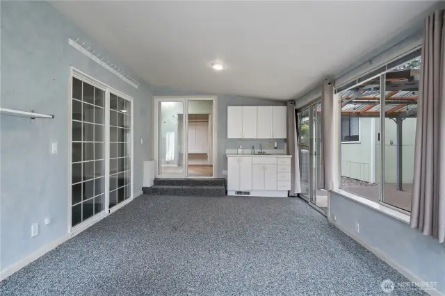 Enclosed room with doors to the garage and to the backyard. Wet bar and cabinets.