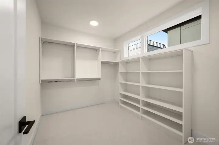 Primary suite walk-in closet with built-in shelving.