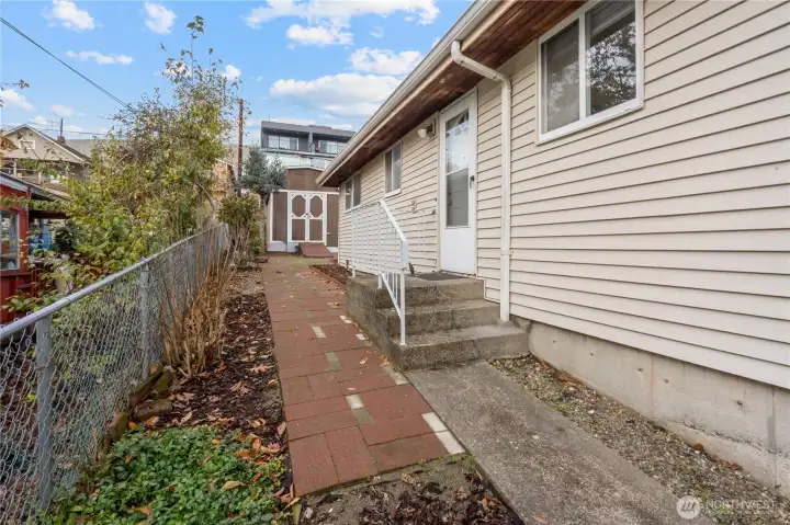 Easy access from the side door takes you through the concrete and paver stone walkways along the side of the home to the backyard and gravel parking pad.