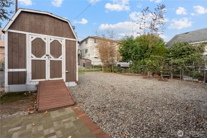 Additional bonus is this spacious gravel parking pad in the back with alley access, all new fencing along the West side of the home and an oversized storage shed for all your toys and tools.