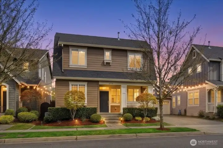 Front exterior at dusk of 13719 33rd Dr SE, Mill Creek WA in Northpointe, showcasing the charming front porch, inviting curb appeal, and former CamWest model home design.