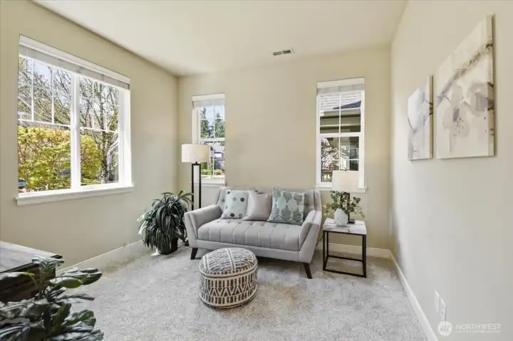 Bright main-level living room with large windows and soft natural light, offering flexible living space in this Northpointe Mill Creek home.