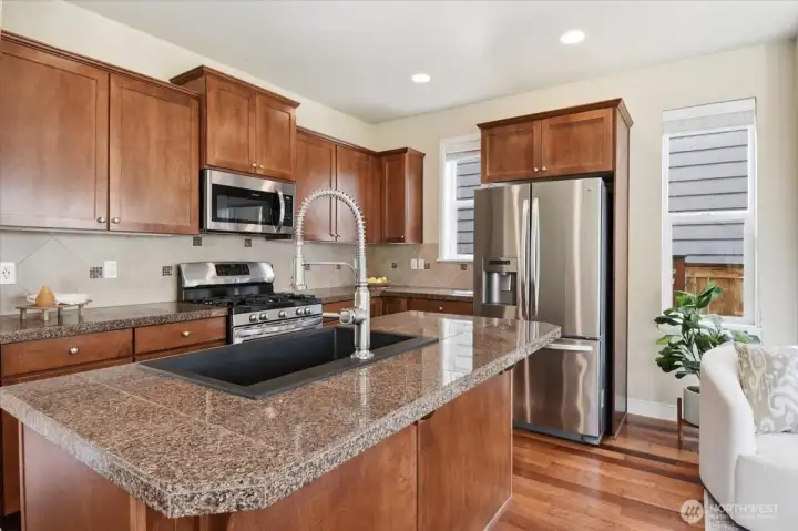 Stylish kitchen with granite tile counters, shaker-style cabinetry, stainless steel appliances, and an oversized island in this Mill Creek home for sale.