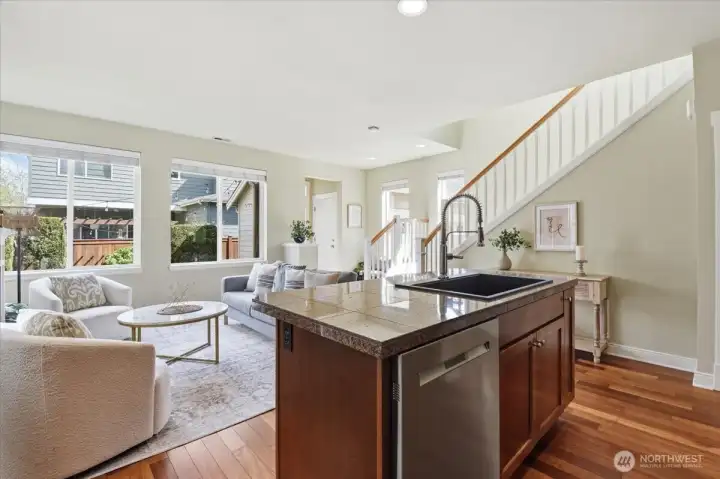 Kitchen and living area connection highlighting the open floor plan, cherry-inspired flooring, and seamless indoor-outdoor flow to the backyard patio.