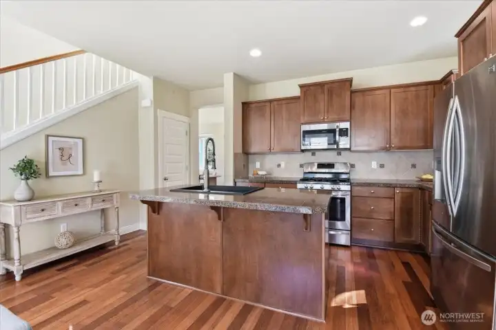Spacious kitchen with center island, gas range, walk-in pantry access, and open views to the main living spaces of this former model home.