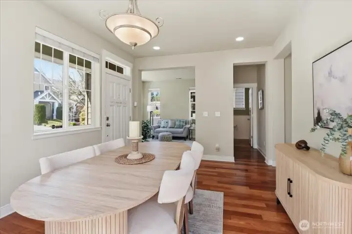 Dining space with front-facing windows and warm flooring, offering a bright setting for daily meals and entertaining.