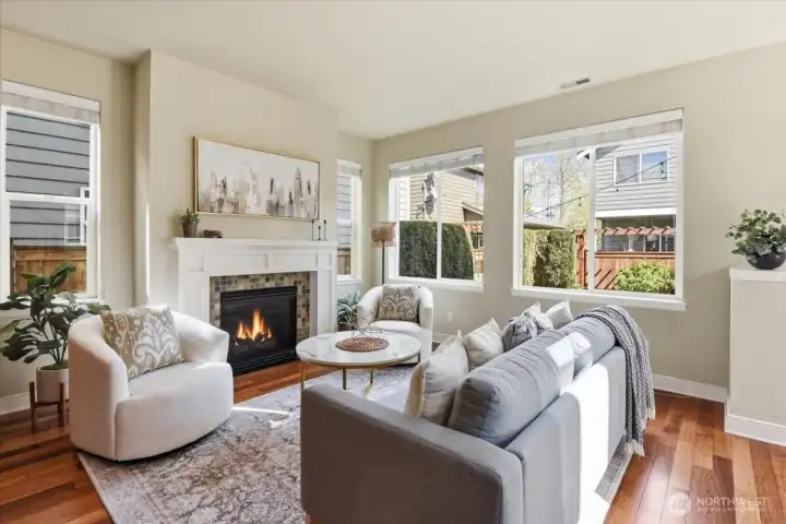 Comfortable family room with gas fireplace, oversized windows, and backyard views, designed for relaxing and gathering.
