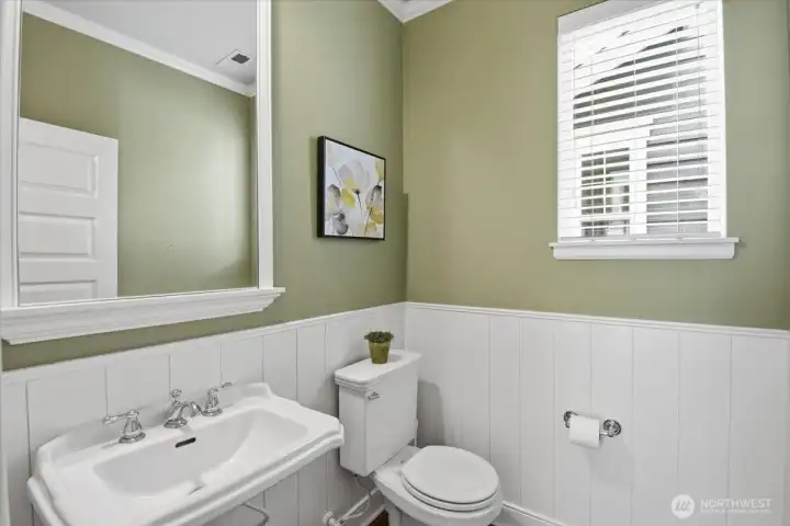 Main-level powder room with pedestal sink, fresh finishes, and convenient guest access.