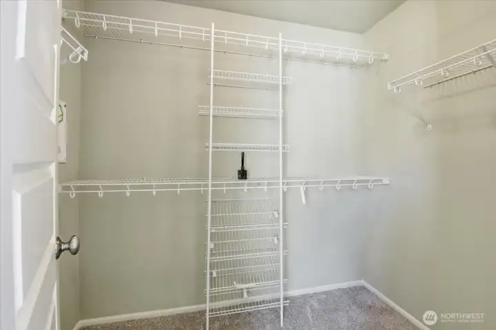 Walk-in primary closet with built-in wire shelving and ample storage for wardrobe organization.