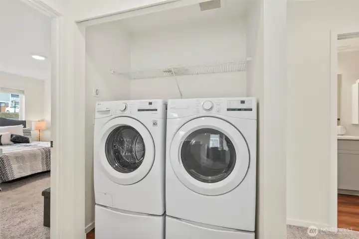 Convenient upstairs laundry with full-size washer and dryer and added shelving for storage.
