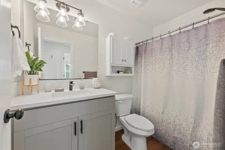 Bright full bathroom with modern vanity, updated lighting, and tub/shower combination.