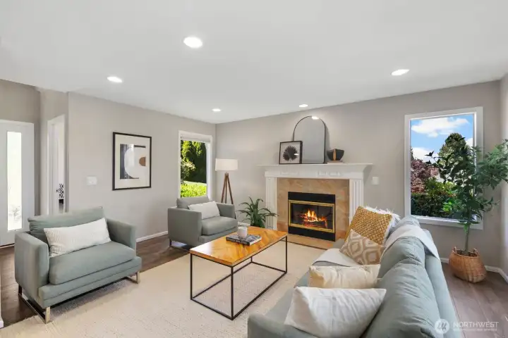 Living room with gas fireplace and greenery out every window.