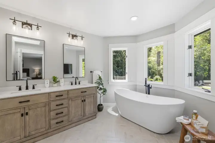 Primary bath = private spa retreat. Featuring a stunning freestanding soaking tub positioned to capture peaceful backyard views, this elegant space invites relaxation and rejuvenation. The oversized dual-sink vanity offers abundant storage and countertop space, complemented by designer lighting, quartz surfaces, and timeless finishes throughout. Large windows fill the room with natural light, creating a bright and serene atmosphere that elevates everyday living.