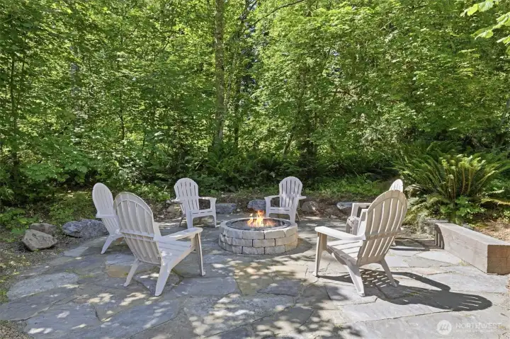 Inviting flagstone patio and fire pit create the perfect destination for evening gatherings, storytelling, and stargazing. Surrounded by mature trees, lush ferns, and natural landscaping, the space offers a peaceful retreat that feels miles away from the city. Whether roasting marshmallows with family or entertaining friends around the fire, this private outdoor oasis captures the essence of Northwest living.