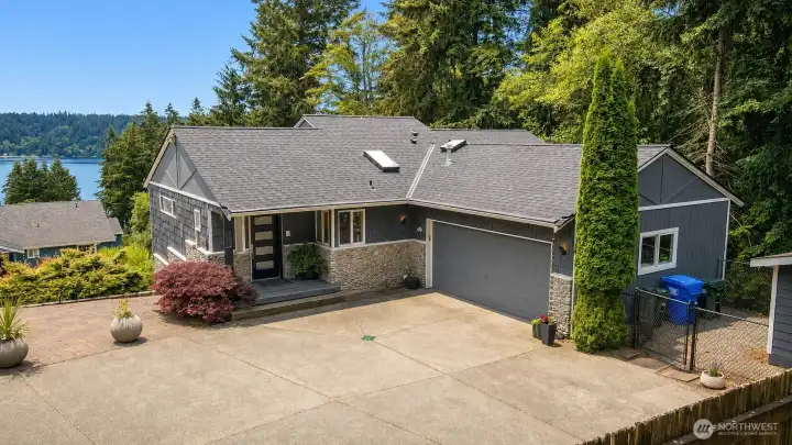 The front of the home set against sweeping Sound views and towering evergreens.