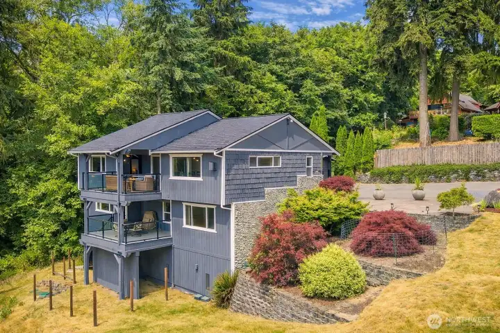 The back of the home showcasing two expansive decks overlooking the surrounding natural beauty.