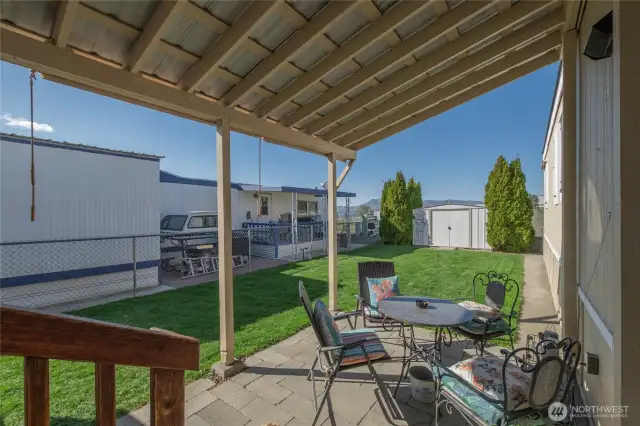 Patio off of deck with lawn and shed all fenced
