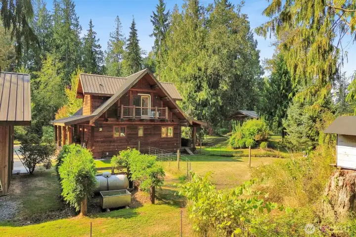 The property features lovely landscaping including fruit trees and a fenced garden area with berries