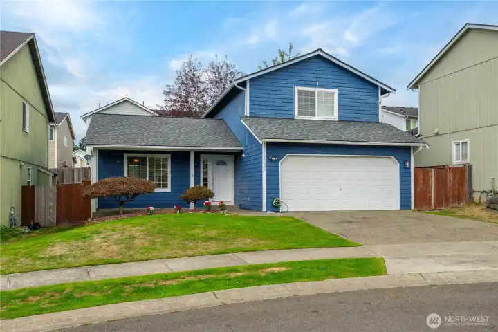 A slightly angled view highlights the wide driveway and front yard, offering extra parking in addition to the garage.