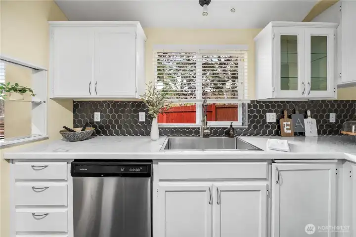 The sink area offers a deep stainless basin paired with an upgraded pull-down faucet. Surrounded by plentiful counter space and cabinetry, this workspace is both stylish and practical.