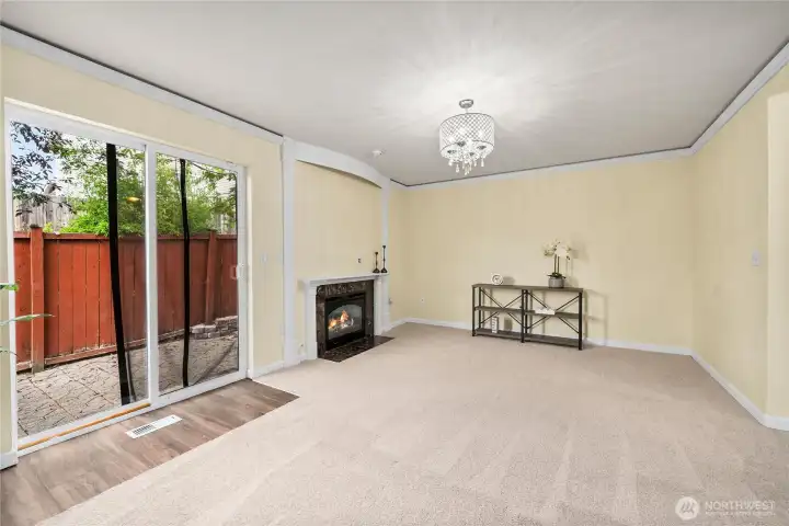 The family room offers a cozy retreat with a sliding glass door that opens directly to the backyard patio. A gas fireplace with a marble surround anchors the space, complemented by plush carpet and a modern light fixture.