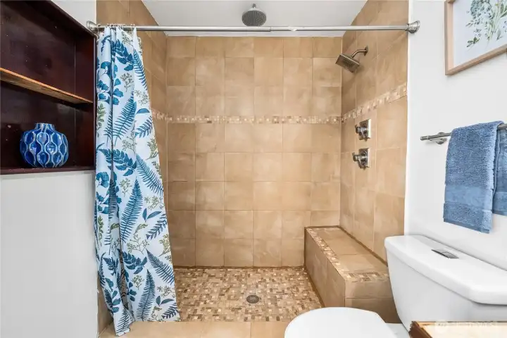 A spacious tiled shower with built-in bench seating offers both function and comfort. The tile surround with decorative accents adds a touch of style.