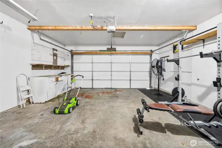 The attached two-car garage offers plenty of room for parking and storage, complete with built-in shelving and workspace. Versatile enough to accommodate vehicles, tools, or a home gym setup.