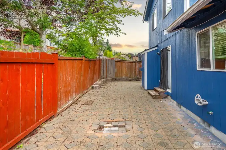 Private fenced backyard with low-maintenance paver patio, perfect for outdoor dining, BBQs, or a cozy evening setup. A mix of greenery and fencing provides both character and privacy.