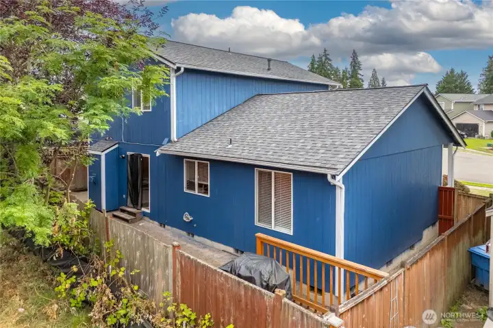 Exterior view of the home shows the fully fenced yard, patio, and side gate access. The home’s crisp blue siding and well-kept roof add to the curb appeal while framing this functional backyard retreat.