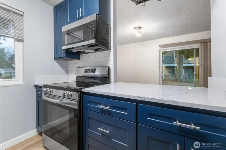 Updated kitchen featuring quartz countertops, custom cabinets, stainless steel appliances, and tiled backsplash.