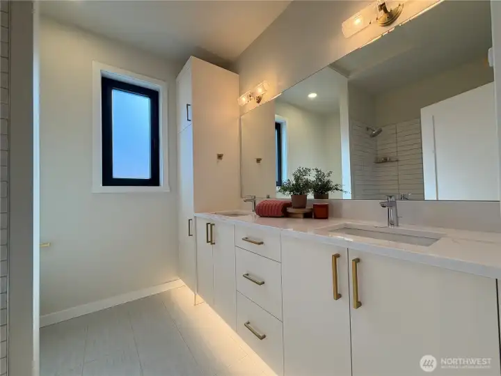 Upstairs full guest bath with double vanity, tiled shower walls and under cabinet lighting.