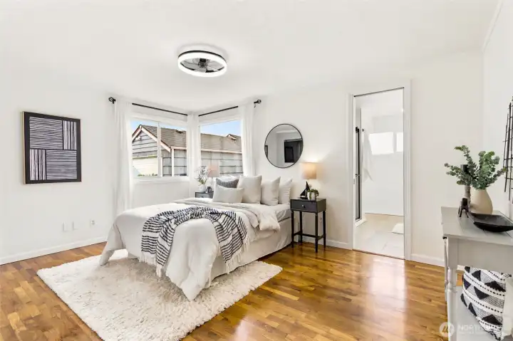 Escape to the spacious primary suite, featuring warm hardwood floors and a calming, light-filled atmosphere.