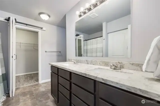 Ensuite to main bedroom, double sinks, counters match the kitchen. Walk in closet at the back behind the barn style rolling door. Shower/tub to the left. Toilet to the back on the right.