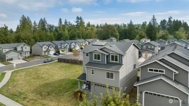 Areal view of front of home with 1 year old solar on the roof and community vacant land next door. Lovely front porch! Save $ with the solar!