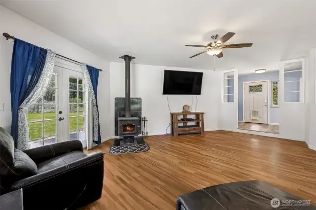 Living room with newer wood stove and French doors that lead out to covered bay window patio.