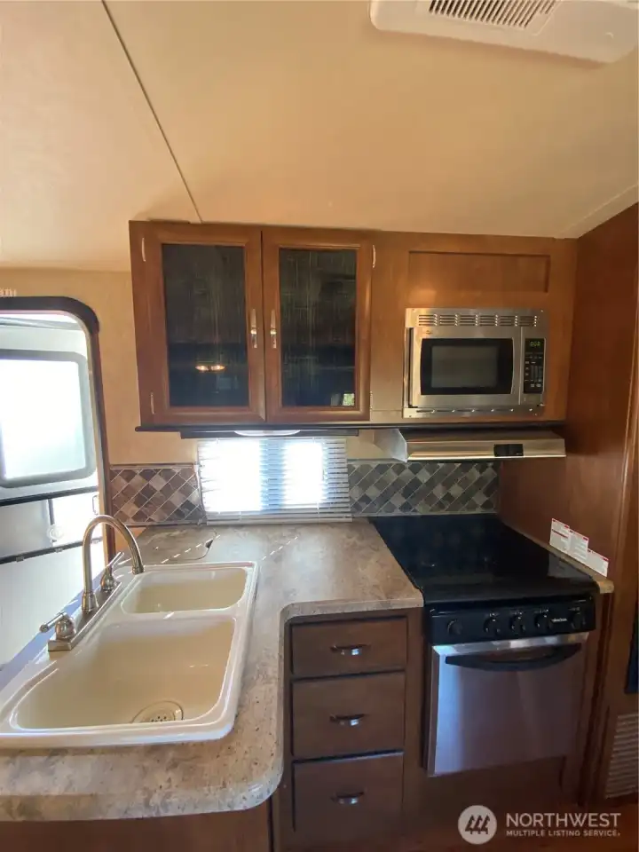 Kitchen w stainless steel appliances. Stove top has cover for flat surface.