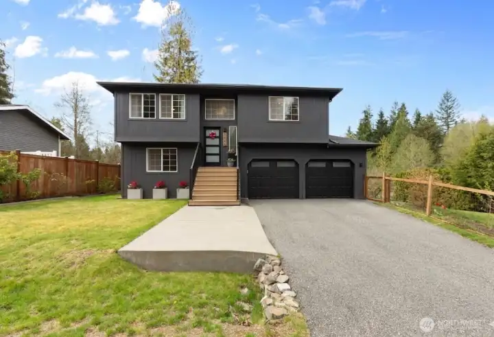 Updated two-story home featuring modern dark siding, a welcoming front entry, new front door and an attached two-car garage with new garage doors. Expansive driveway, neat landscaping, and mature trees provide a polished exterior with a private Northwest setting.