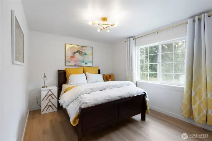 Second bedroom filled with natural light, featuring updated flooring, modern lighting, and a large closet with new contemporary doors, offering a comfortable and versatile living space.