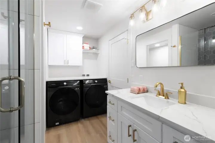Beautifully remodeled primary bathroom featuring quartz countertops, modern cabinetry, and a walk-in shower with stylish finishes. Added convenience with in-bath laundry.