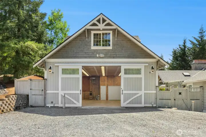 Front of the detached shop/garage. Inside center door is a toilet, to the right is a utility sink & full washer & dryer. Outside storage area to the left.