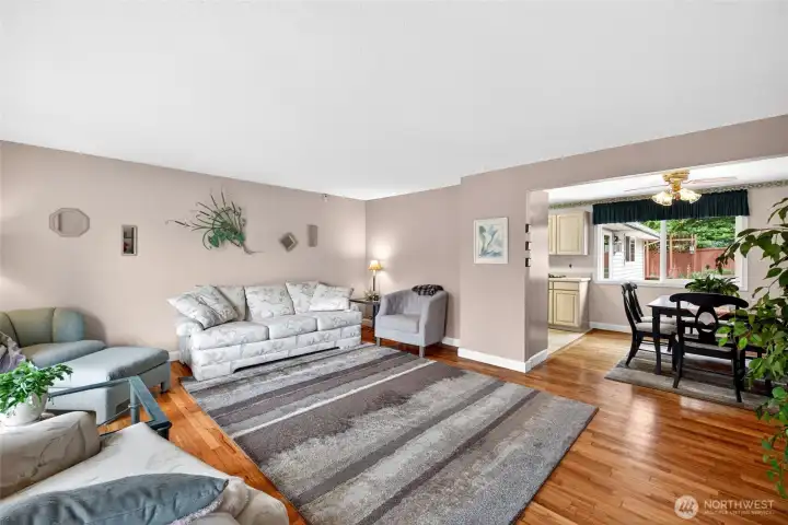 Spacious living room with warm hardwood flooring and an open layout that flows seamlessly into the dining area, creating an inviting space for everyday living and entertaining.
