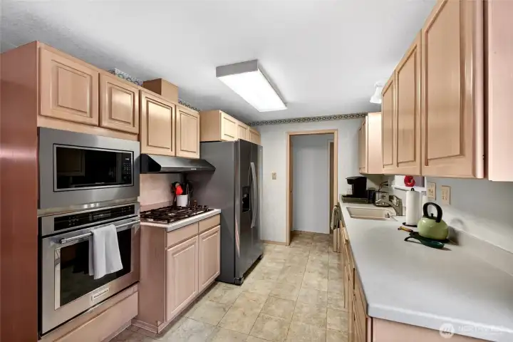 Functional galley-style kitchen with extensive cabinetry, generous prep space, and stainless appliances ready for everyday cooking and entertaining.