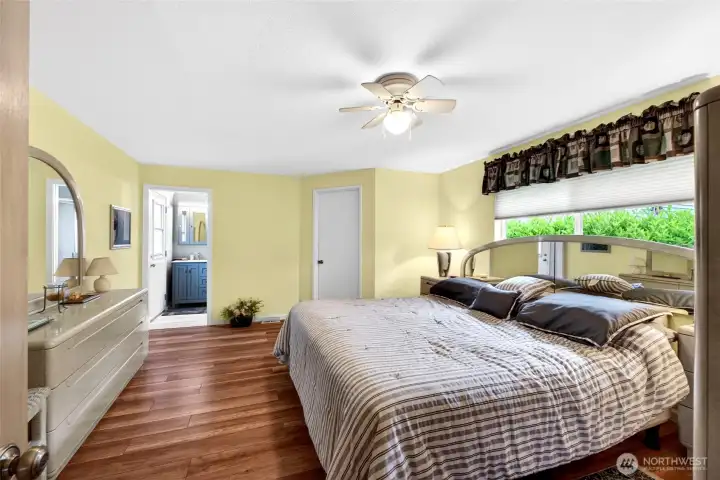 Spacious primary suite filled with natural light, featuring wide-plank flooring, a beautifully updated ensuite bath, and an oversized walk-in closet.