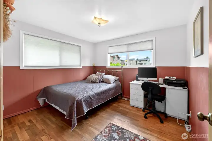 Comfortable secondary bedroom with hardwood flooring, large windows for natural light, and flexible space for guests, remote work, or everyday living.