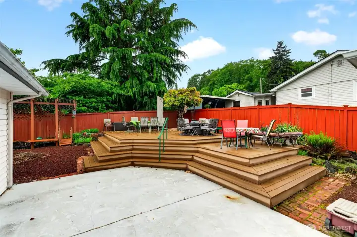 Private fenced backyard features a spacious multi-level deck, sideyard, and mature landscaping for year-round enjoyment.