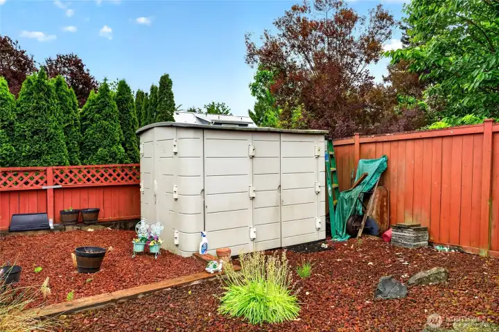 Low-maintenance backyard design with storage shed offers extra space for tools, gardening supplies, or seasonal décor.
